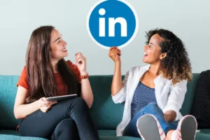 Two girls sitting and showing finger at the LinkedIn logo